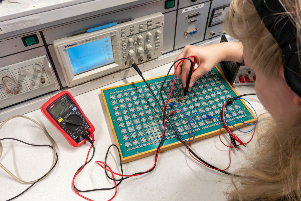 Opiskelija työstää elektroniikkalaitetta.