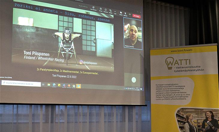 Valkokangas, jossa näkyy videopuhelunäyttö, jossa kuvassa Toni Piispanen sekä hänen esityksensä.