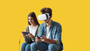 Keltaisen tausta edessä kaksi henkilöä istuu, toisella on päässään ja käsissään VR-lasit ja -ohjaimet, toinen katsoo kännykkää.